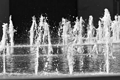 Fountain water jets rise dynamically against dark background Stock Photos