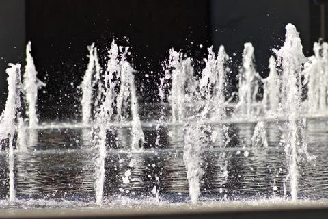 Fountain water jets rise dynamically against dark background Stock Photos