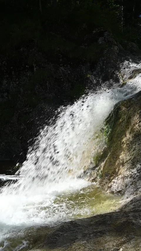 A fountain-like waterfall in direct sunlight, vertical shot, slow motion Stock Footage 260919574