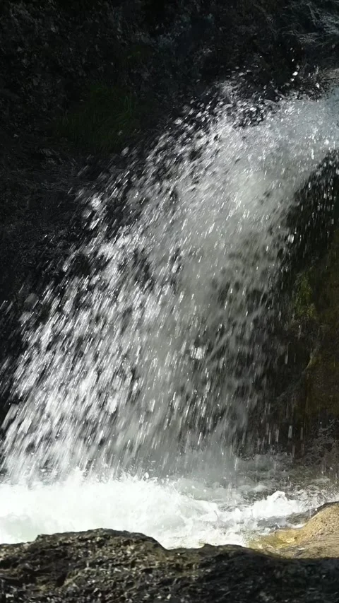 A fountain-like waterfall in direct sunlight, vertical shot, slow motion Video stock 260919756