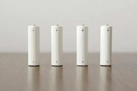 Four AA batteries on the table upright stand Stock Photos