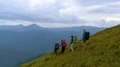 The four active people with backpacks walking down on the mountain 4k or 4k+ Resolution