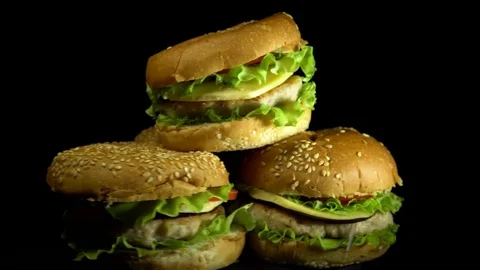 Four appetizing burgers revolve on a black background. Stock Footage 84073234