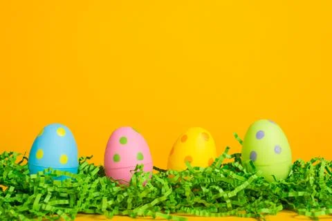 Four assorted color easter eggs on a bright yellow background Stock Photos