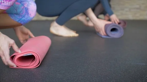 Four athletes roll out the yoga mat in yoga class Stock Footage