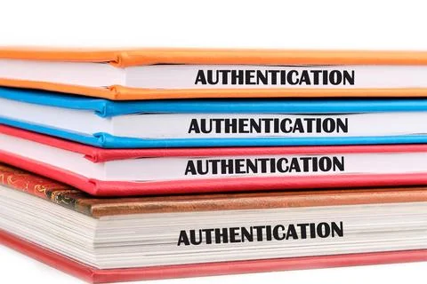Four binders stacked vertically display the word AUTHENTICATION on their sp.. 库存照片