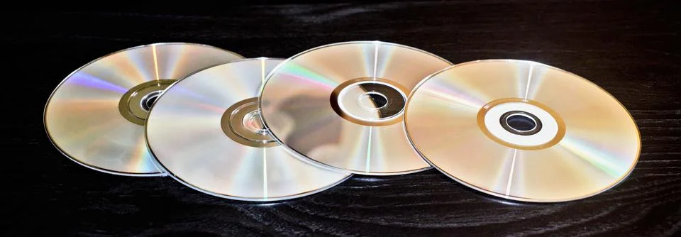 Four blank CD discs spread out and isolated on a black table. Foto stock