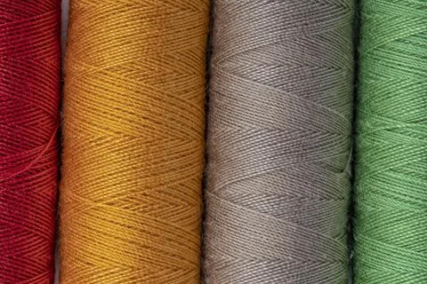 Four bobbins of sewing thread of red green orange and brown colors Stock Photos