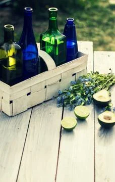 Four bottles of drinks in a white basket and fruits on a white table Stock Photos