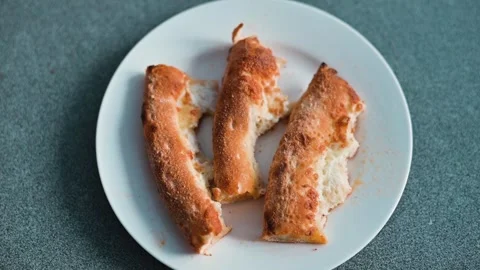Four bread sticks are placed on a white plate on a flat surface. Pizza slices, Stockbeeldmateriaal 338290179