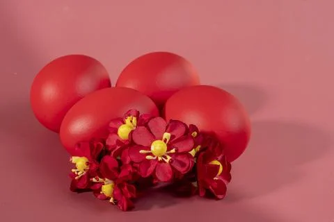 Four bright red painted Easter eggs decorated with small artificial flowers.. Stock Photos