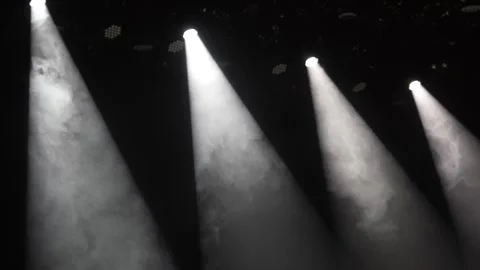 Four bright white spotlights shining through smoke in dark stage Stock Footage 346303874