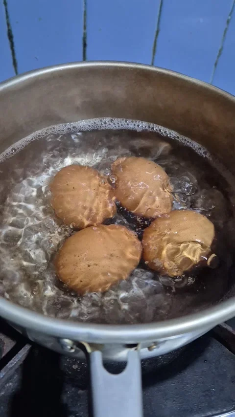 Four brown eggs boil in water on stove Stock Footage 342079654