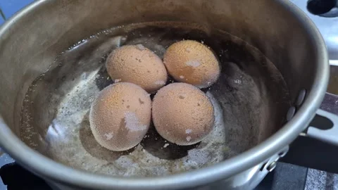 Four brown eggs boiling in water on stove Stock-Footage 342079653