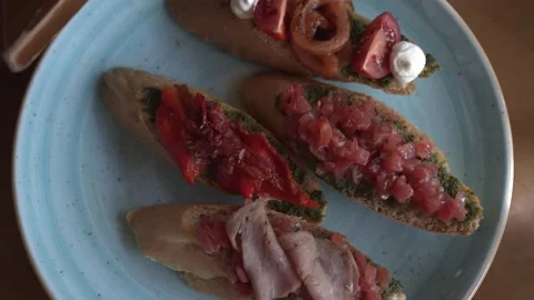 Four bruschettas with different red fillings on a blue round plate Stock Footage 204097028