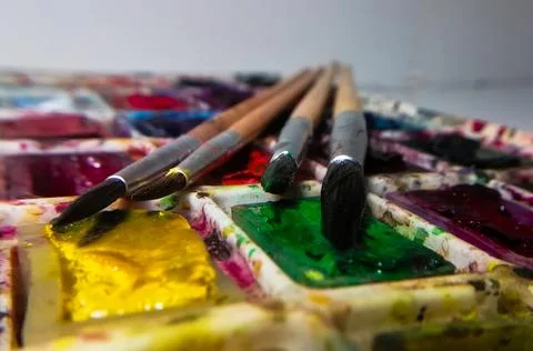 Four brushes on a background of multi-colored watercolor paint Foto stock