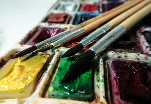 Four brushes lie on a background of multicolored watercolor paints Foto stock