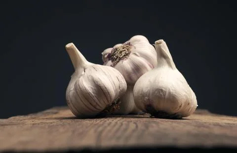 Four bulbs of garlic on a rustic kitchen table Stock Photos