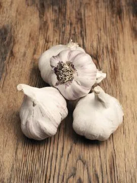 Four bulbs of garlic on a rustic kitchen table Stock Photos