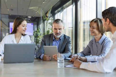 Four business professionals using laptop on desk discussing strategy company 스톡 사진