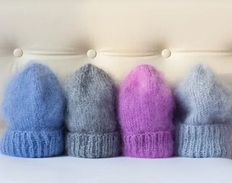 Four caps of different colors connected by hand from mohair Stock Photos