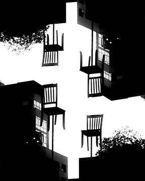 Four chairs appear to be floating against a high-contrast cityscape backgro.. Stock Photos