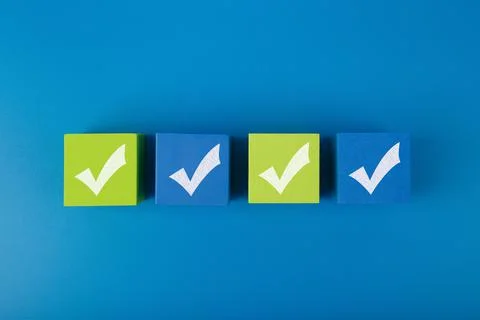 Four checkmarks on four toy blocks in the middle of blue background Stock Photos