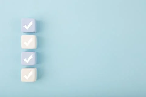 Four checkmarks on light toy blocks against pastel blue background with copy Stock Photos