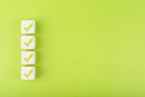 Four checkmarks on white cubes against bright green background with copy space Stock Illustration