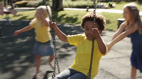 Four children playing on swings in park. Stock Footage