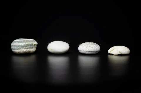Four clean and empty white ocean beach rocks and stones on black background Stock Photos
