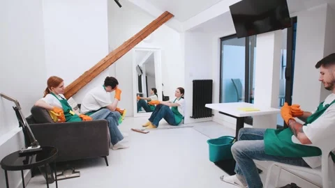 Four cleaners take a break during a cleaning session in a modern living room wit Stock Footage 301520192