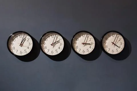 Four clocks on the black wall Stock Photos