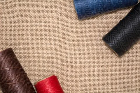 Four coils of threads on a linen background. Red, blue, brown and black threads Stock Photos