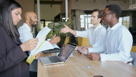 Four colleagues discuss financial issues in an office space. One man shakes Stock Footage 335732742
