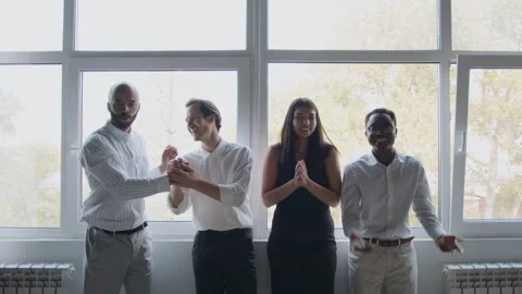 Four colleagues stand by a window in an office, celebrating their success 스톡 동영상 335734251