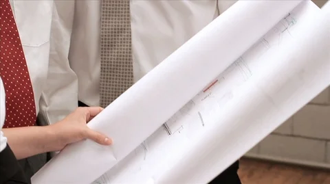 Four colleagues standing together looking seriously at building plans. Vídeos de archivo 88407139