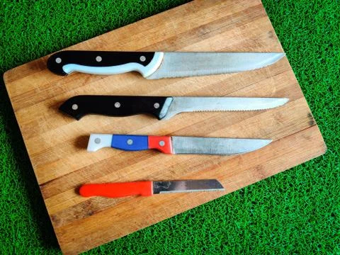 Four colored different sizes of knives kept on chopping board. Stock Photos
