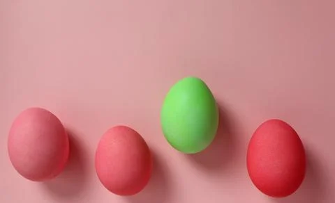Four colored eggs on a pink background during an Easter decoration activity in a Stock Photos