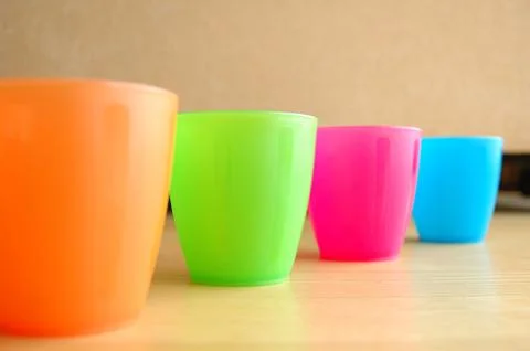Four Colourful plastic mugs standing on floor Stock Photos