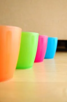 Four Colourful plastic mugs standing on floor Stock Photos