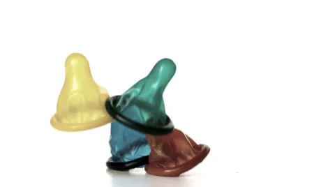 Four condoms falling on white background Stock Footage