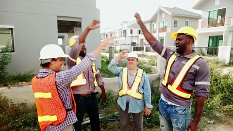 Four construction workers in hard hats hands clasped together in the center Stock Footage 327695384