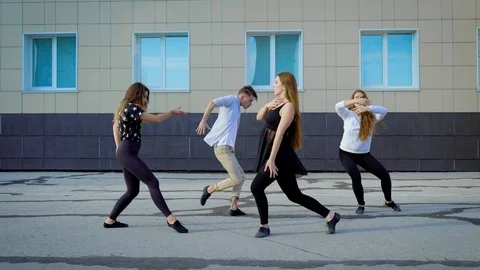 Four contemporary dancers is rehearsing modern dance on a street in front of Stock Footage