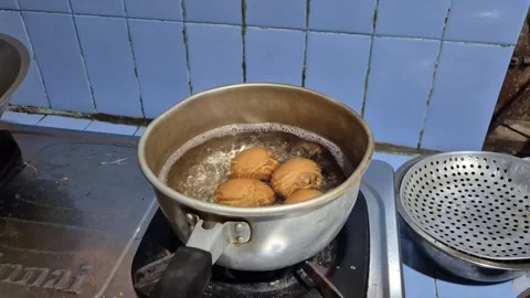 Four cracked eggs boil in a bubbling pot on stove Stock-Footage 342346978