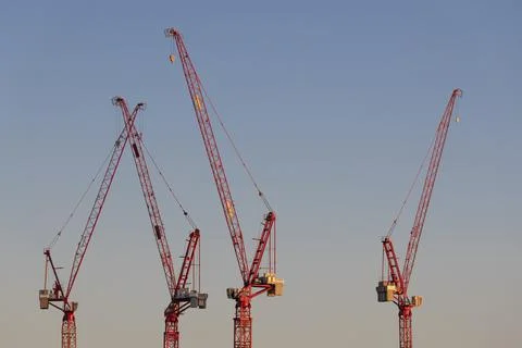 Four cranes in the evening light on a large construction site in the west of Stock Photos