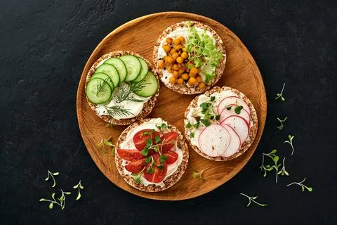 Four crispy buckwheat bread with cream cheese, radish, tomato, chickpea, cucu Stock Photos