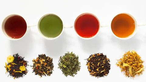 Four cups of tea  on white   table with large assortment of herbal, flower, b Stock Photos