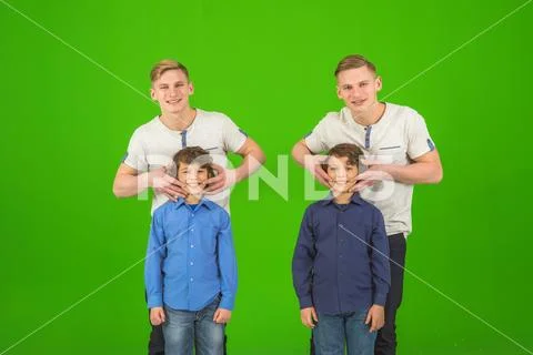 The four cute brothers stand on the green background Stock Photos