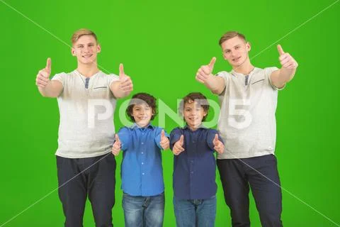 The four cute brothers stand on the green background and thumb up Stock Photos